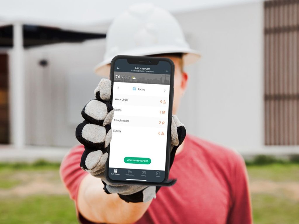 construction worker using daily log app in field.